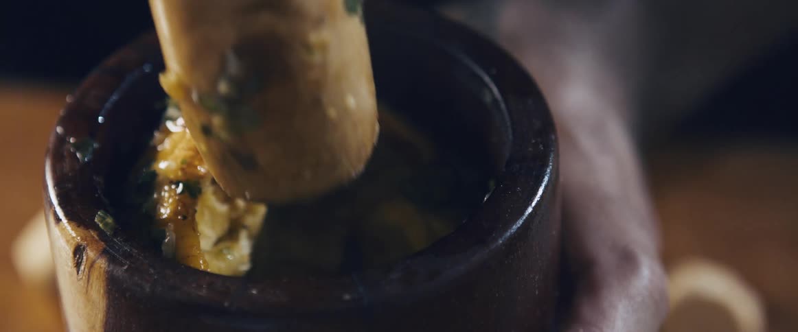 A pestle kneading food in a small bowl