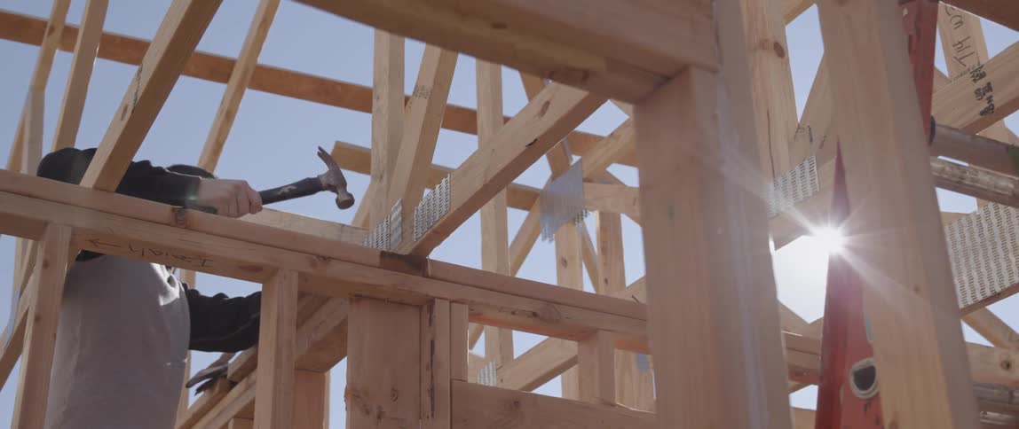 Worker hammering nail into frame of a building