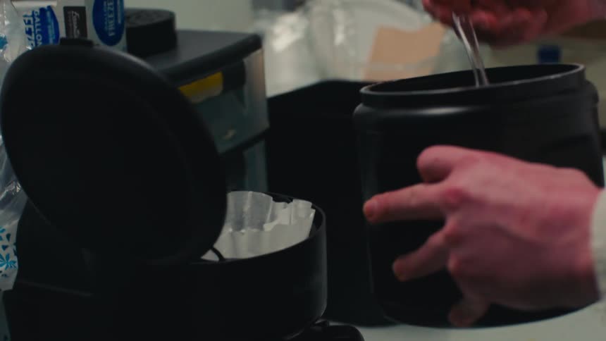 A person is filling the coffee maker with ground coffee