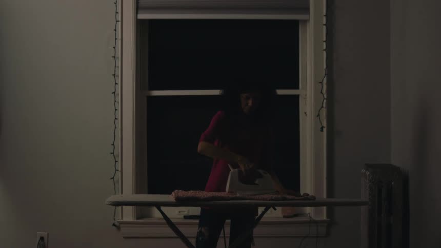 Woman in a room ironing clothes