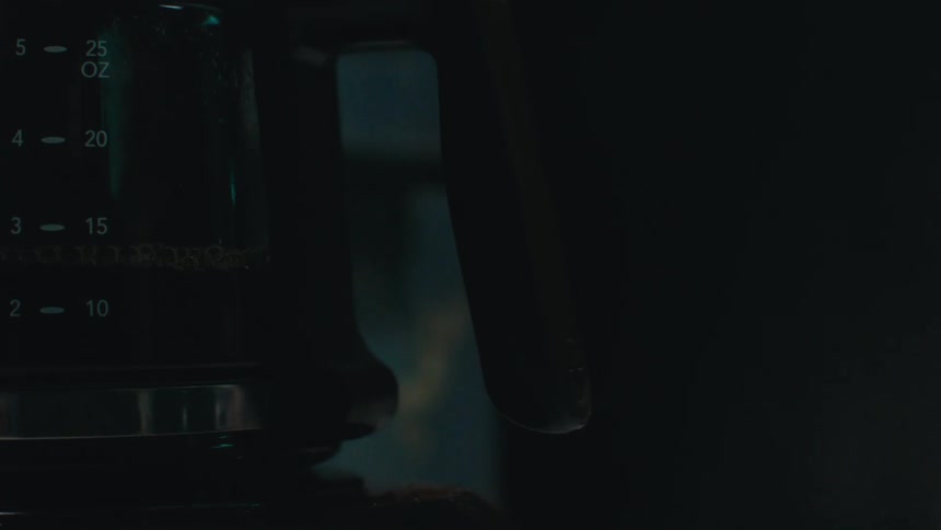 An electric kettle in the dark reflecting someone moving near it