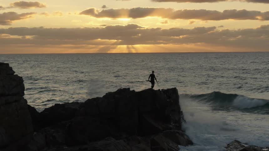 A man climbs over the rocks to the ocean