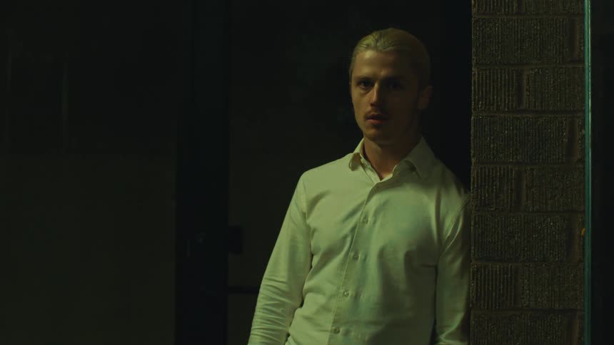A man smokes a cigarette outside of a brick building