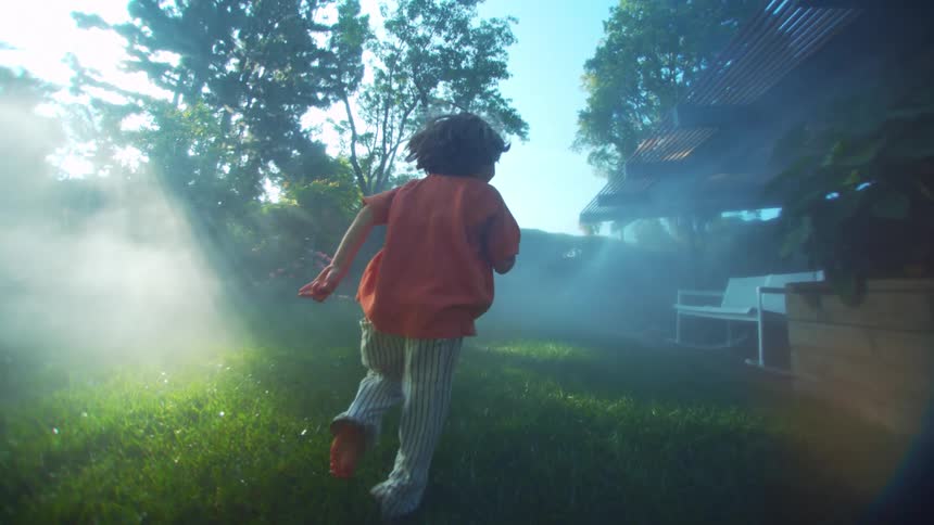 Little boy running on the grass in the backyard