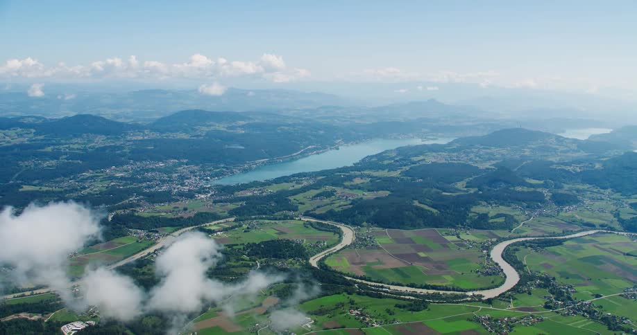 A winding river carving its way through a lush green valley passes by small towns