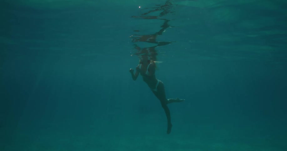 Blonde woman swimming submerged in a blue ocean