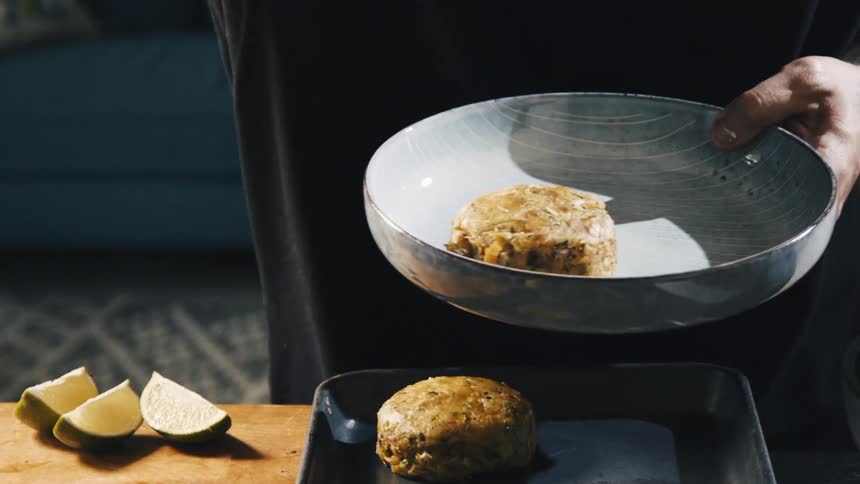 A persons hand plate meat onto a gray bowl