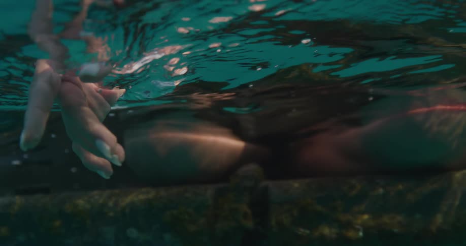 A woman slowly moves her hand side to side just beneath the waters surface