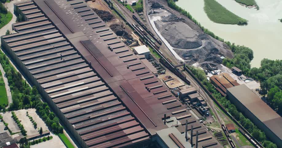 Aerial panorama of an industry with train tracks around it and a lake