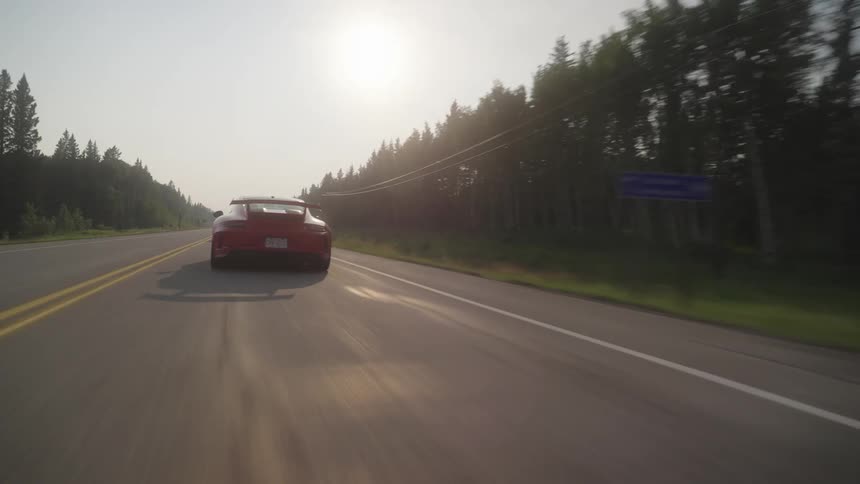 Sports cars traveling along an extensive highway with trees around