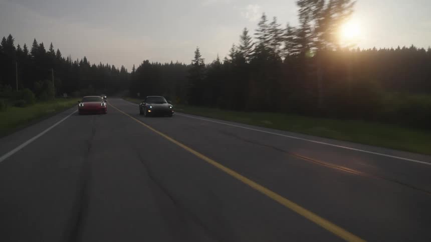 A sports car speeds past another one on the highway