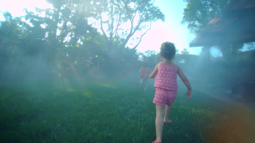 Two children running on the grass in the backyard of a house