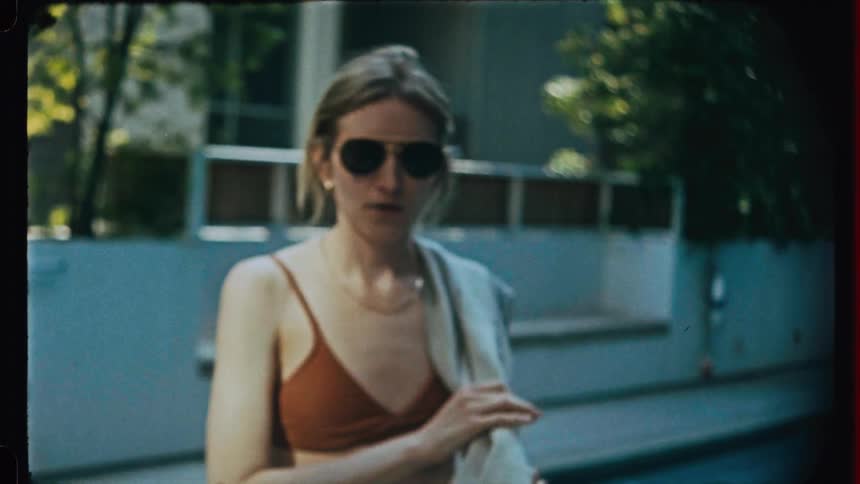 Woman near outdoor pool angrily puts her sunglasses on before speaking