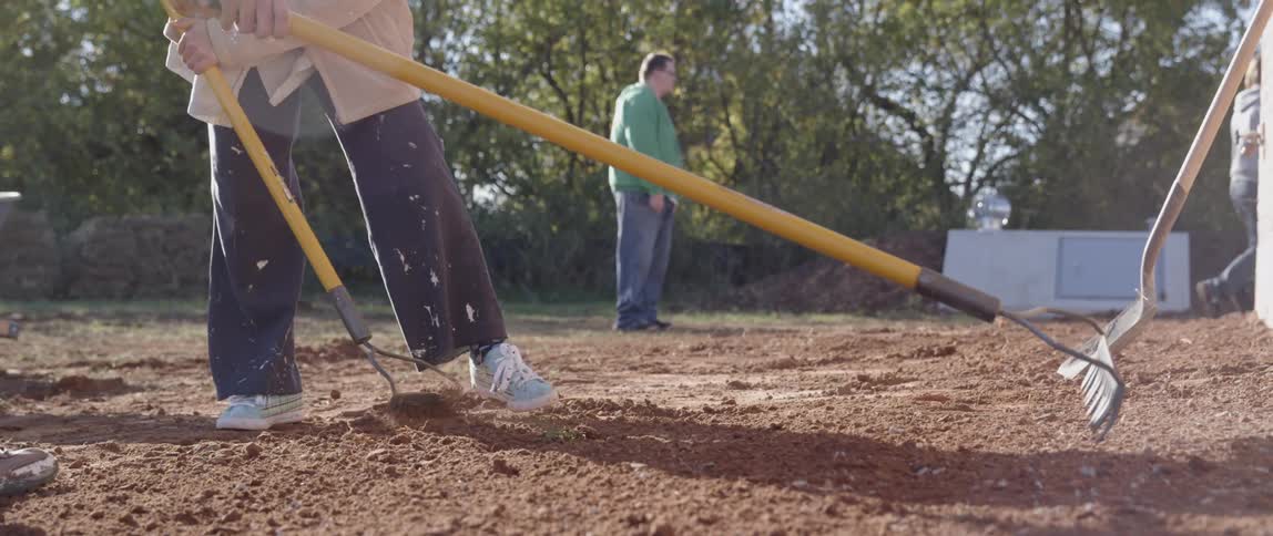 People rake the dirt for a garden