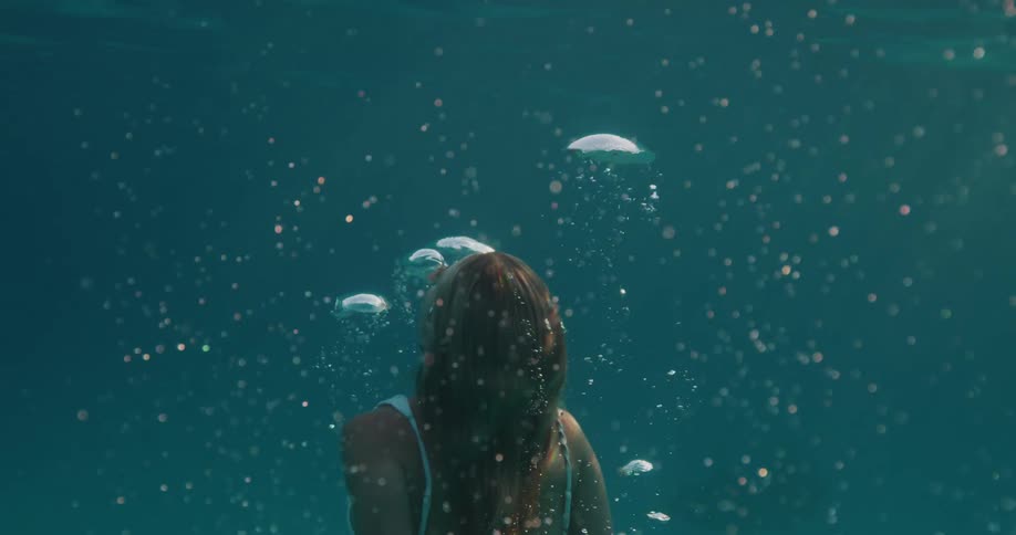 Woman submerged in the ocean with air bubbles rising