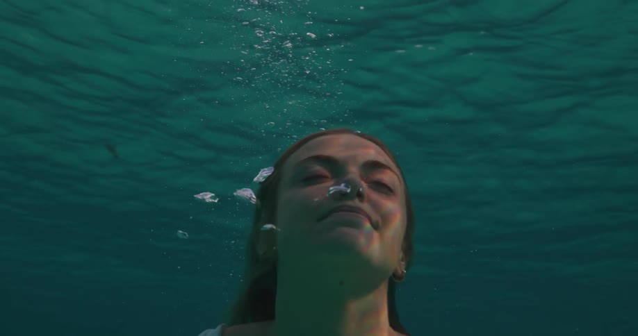 A woman swims to the surface of the water