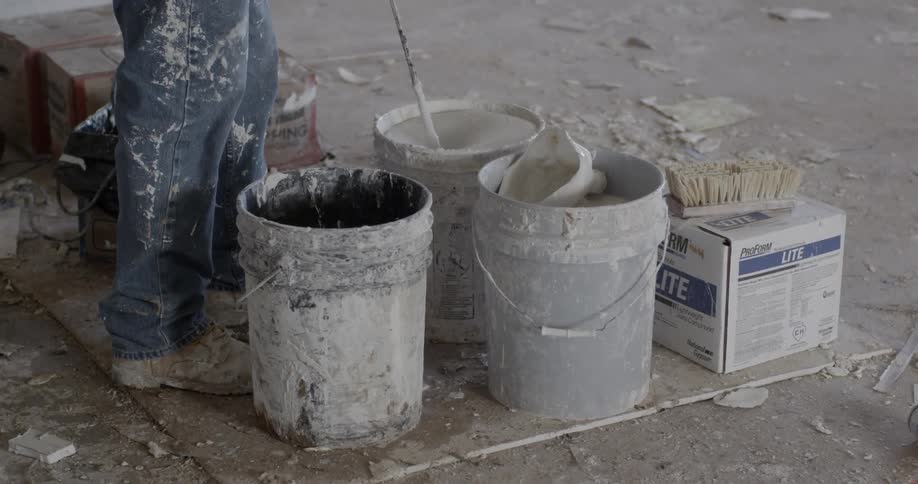 Man using mixer to mix paint in bucket