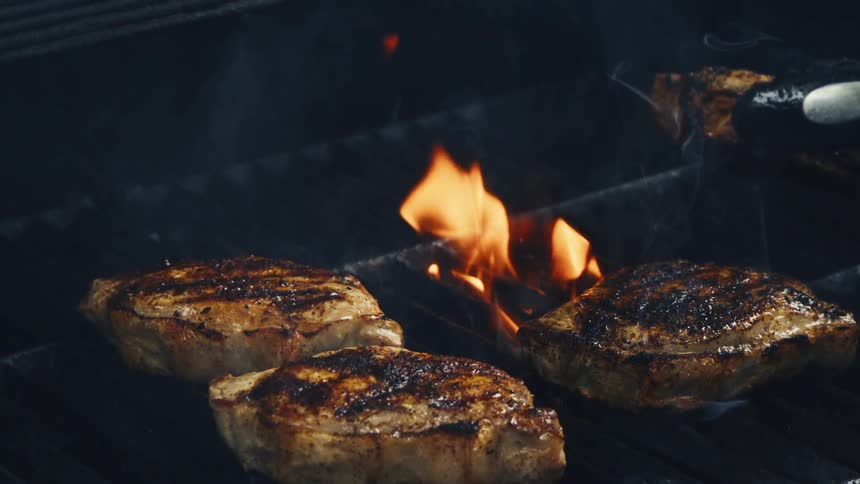 Steaks are sizzling on a barbecue grill