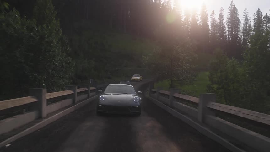 Sports and luxury cars crossing a bridge with mountains and trees around