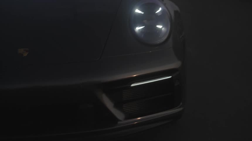 A black porsche car races down a dark highway at night