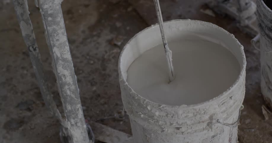 Paint is being stirred in a bucket
