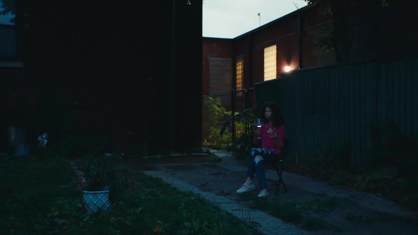 Woman sitting alone outdoors near building drinks a beverage