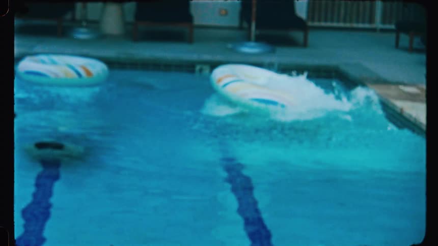 Two young men diving into a swimming pool