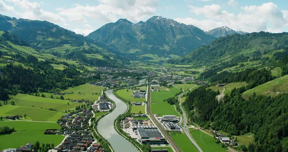 Aerial panorama of a residential neighborhood on the edge of a canal and surrounded by mountains with vegetation