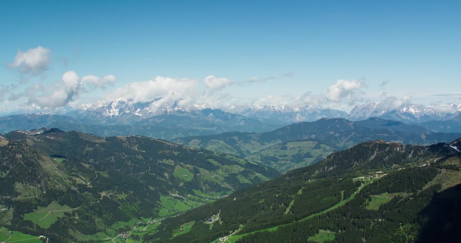 Aerial panorama of mountain ranges with snowcapped peaks and greenery