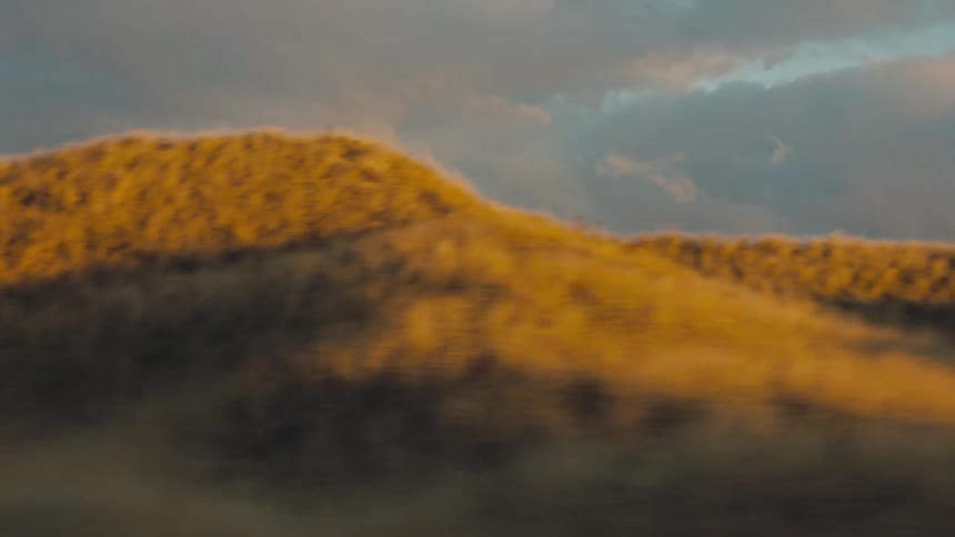Moving view of mountains and trees with reflection of the late afternoon sun