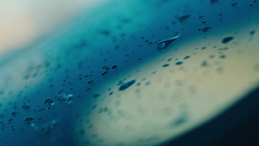 A closeup of water droplets on a surface with a gradient of blue tones