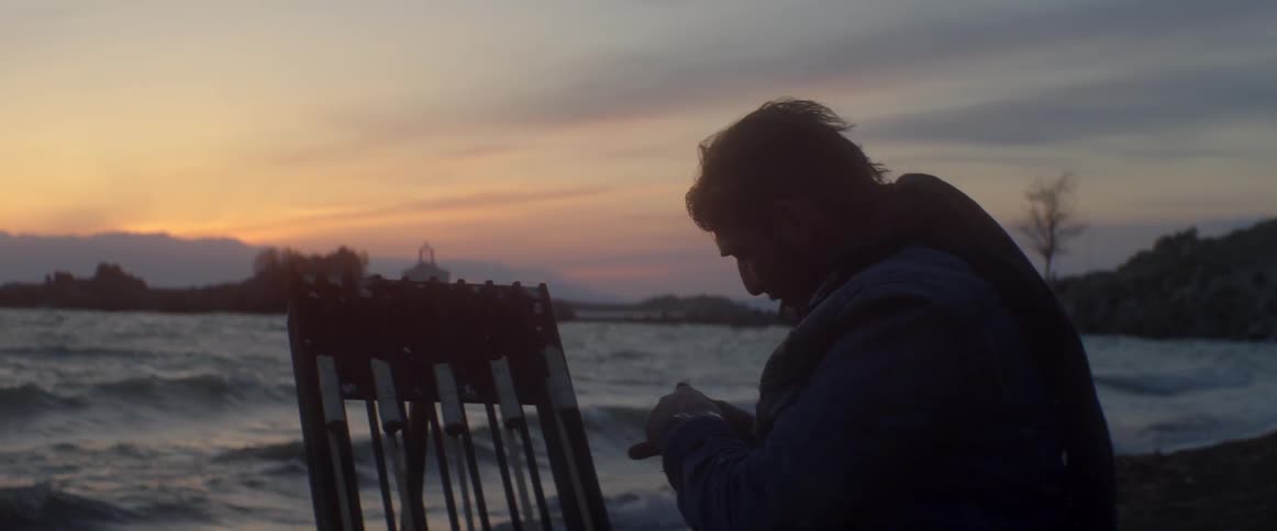Man setting up something at sunset by the water