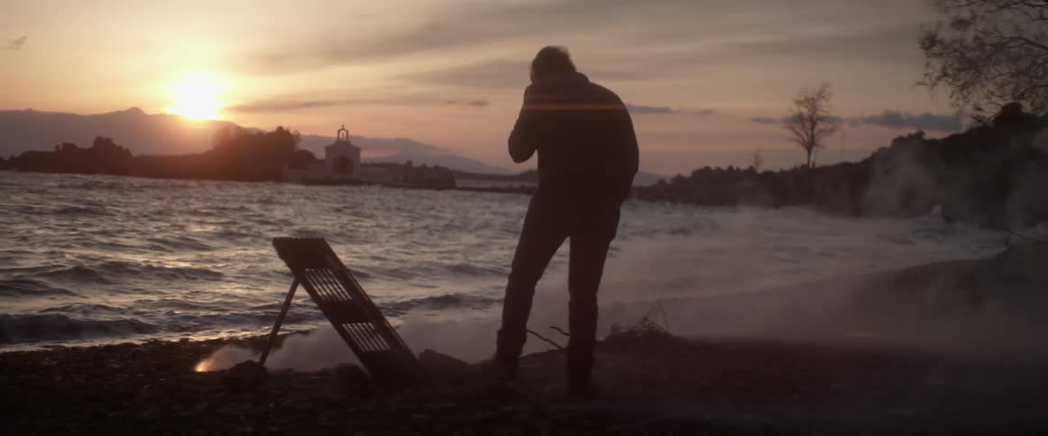A man on a beach at dusk sets of fireworks