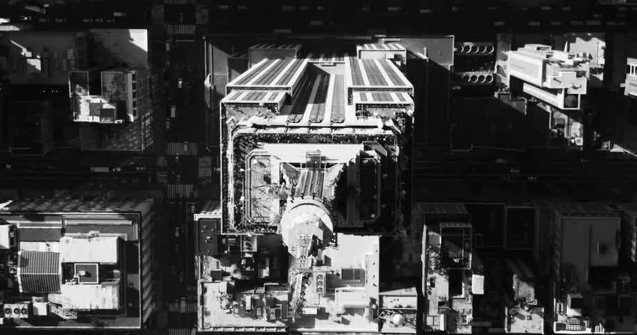 An aerial view of a large commercial building with a tower on top and in monochromatic tones