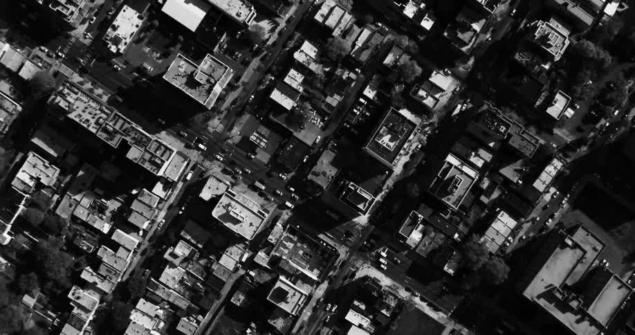 An aerial view of several houses and buildings in a city in black and white tones