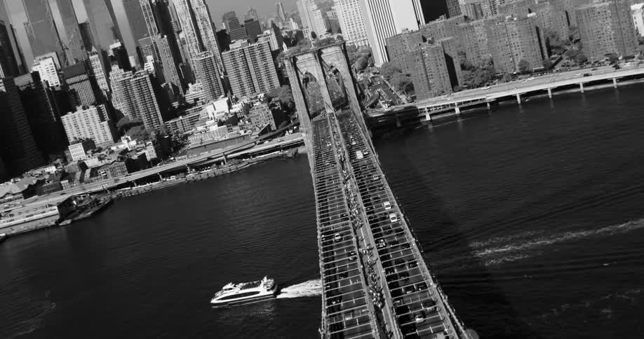 Aerial panorama of an extensive bridge over the sea with vehicle traffic and a metropolis with skyscrapers in the background