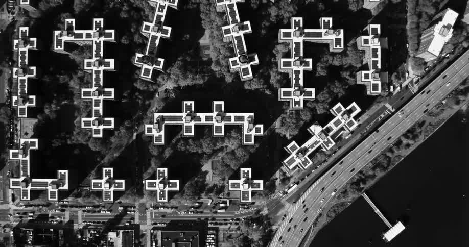 An aerial view of several condominium buildings among many trees and everything is in black and white tones