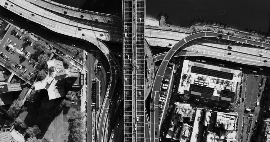 An aerial view of a freeway with many cars passing by and a bridge that goes over the water