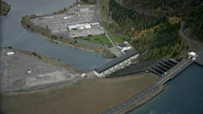 A large dam with huge pipes that descend the water into a lake