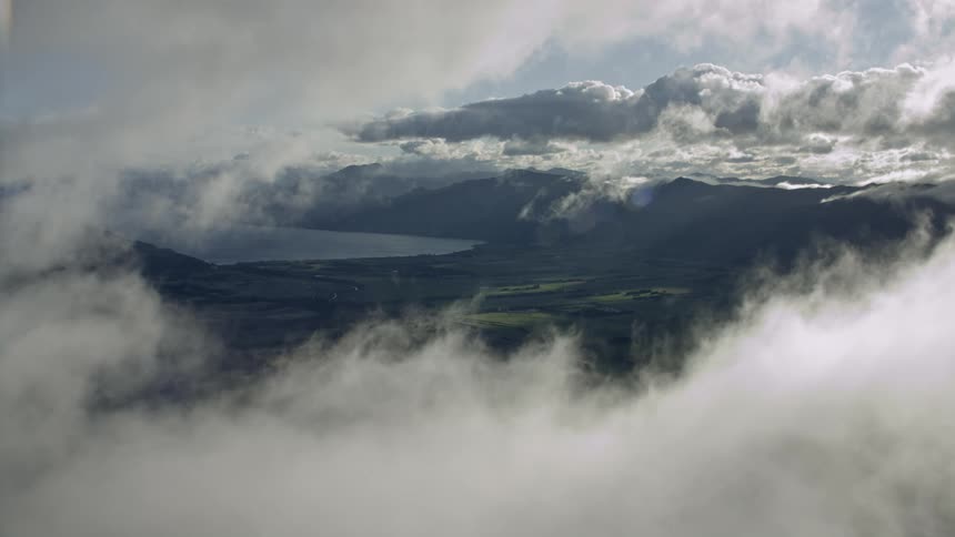 An aerial view of an agricultural landscape with mountains in the background near the coast
