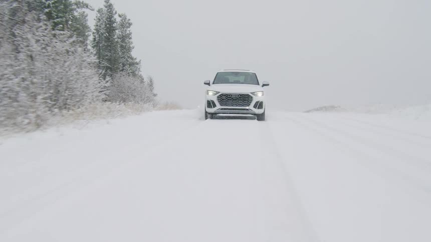 Vehicle drives along snow covered road past ice crusted trees on a winter day