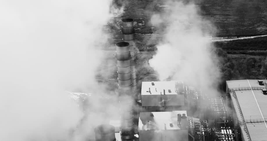 Two industrial towers releasing a lot of smoke in an industry in black and white tones