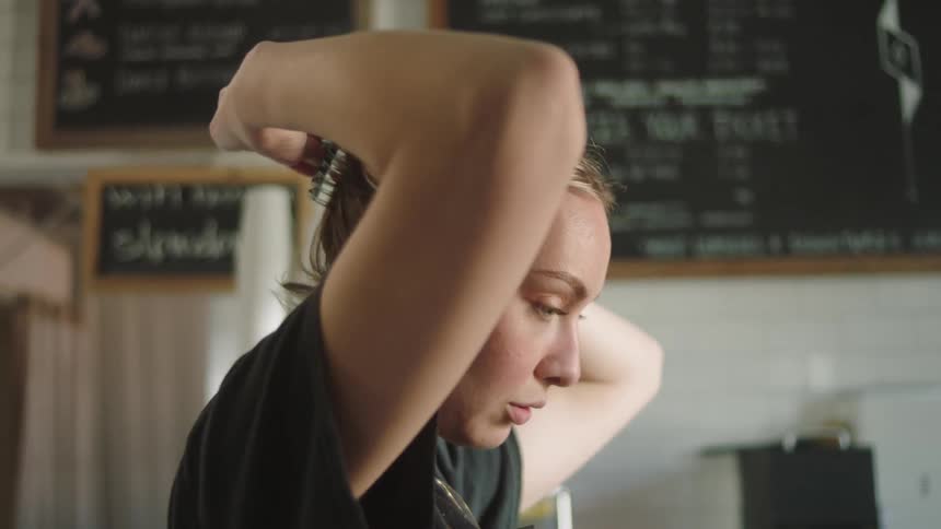 A cafeteria worker puts on an apron and readies up to open shop