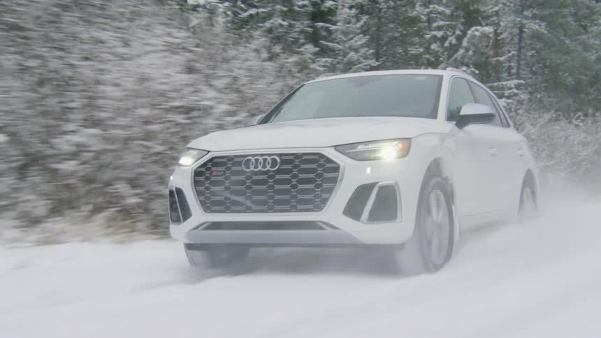 White car traveling down a snowcovered road with trees around