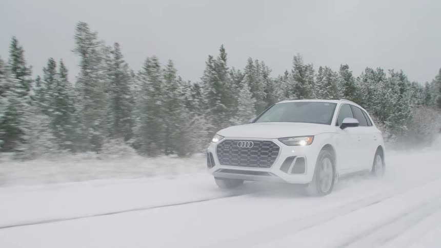 White audi suv drives snow covered tree lined road