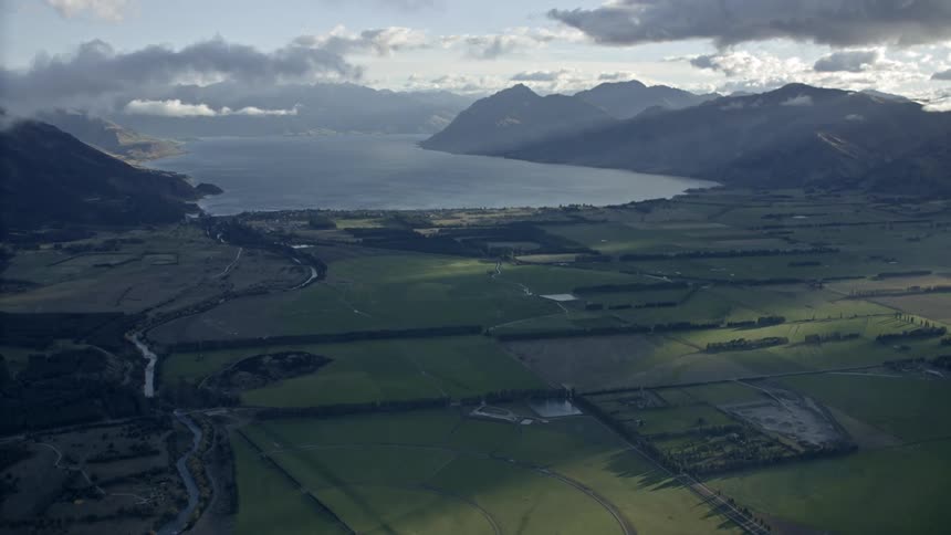 Farm fields near a coastal area surrounded by mountains