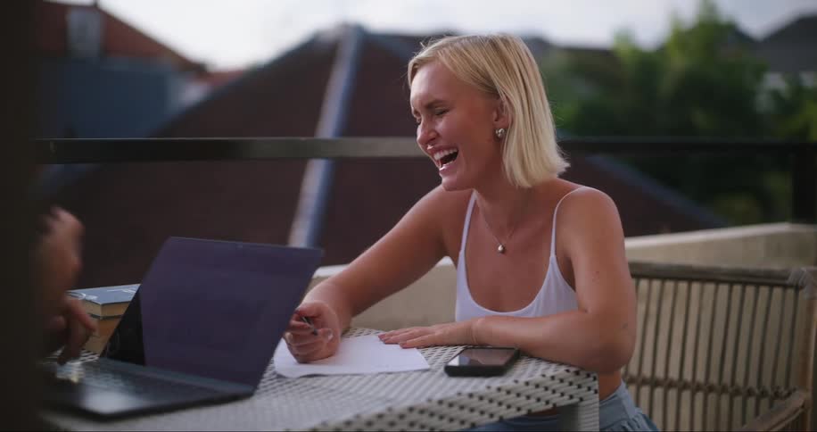 Man and woman working on balcony laugh together