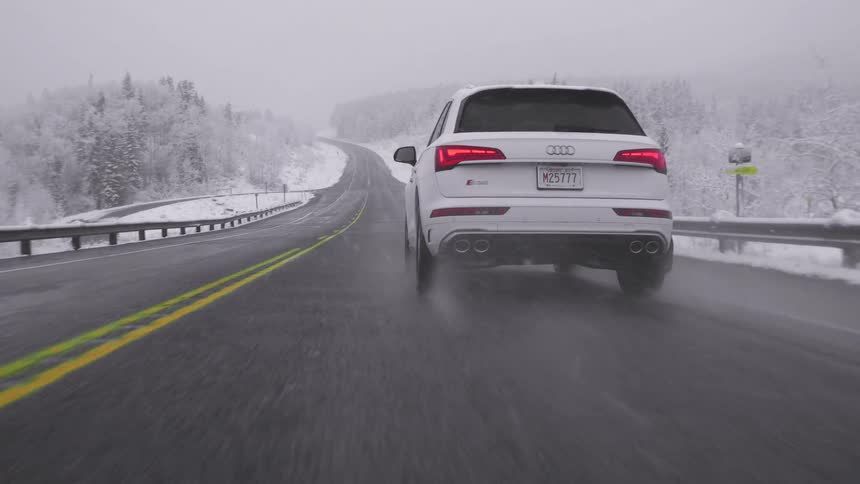 A white car brakes hard on a road slick with melted snowflakes