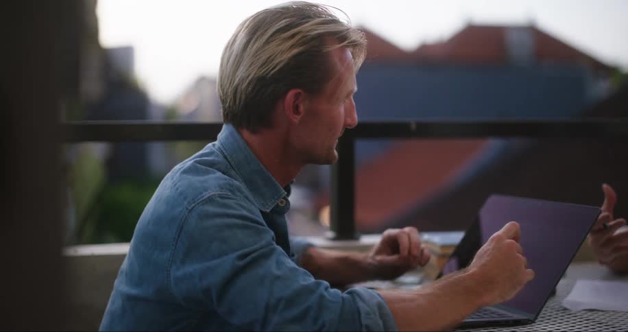 A blonde woman is sitting and talking to a man in front of her and he has a notebook in front of him and is listening to a woman