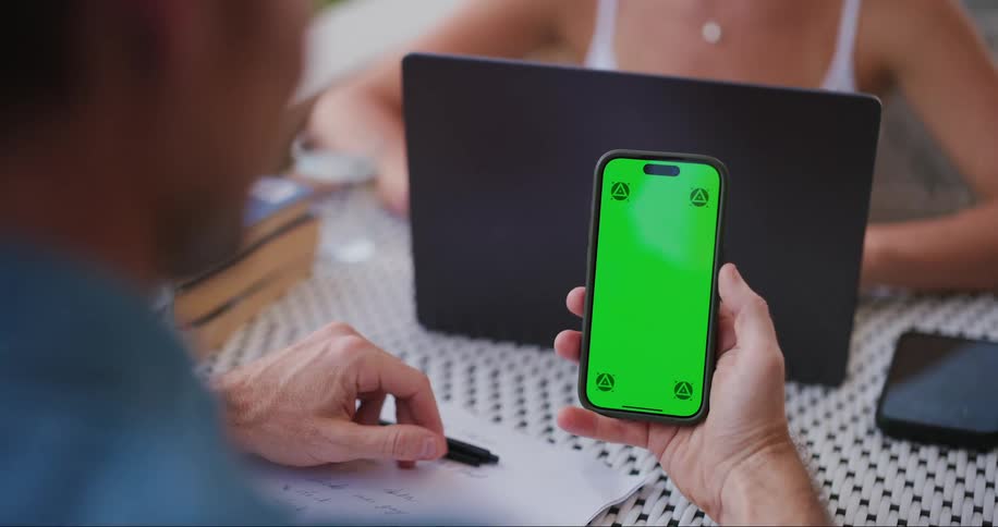 A person holding a cell phone with a completely green screen and swiping the screen